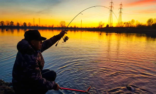 在日落时在池塘里钓到鱼的渔夫 — 图库照片