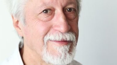 beyaz saçlı yaşlı beyefendi gülümsüyor ve kamera bakıyor