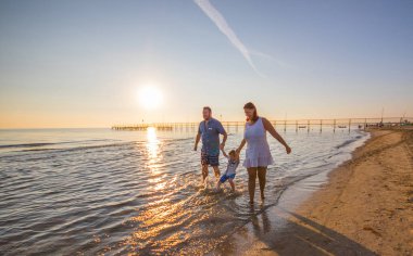 Sahilde günbatımı üzerinde mutlu aile