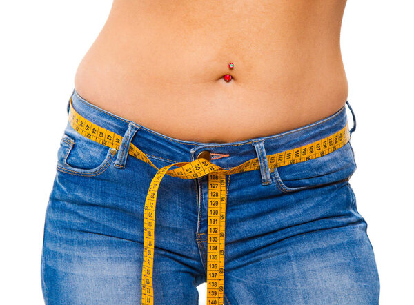 a slender young woman in jeans with a tape measure after a successful diet