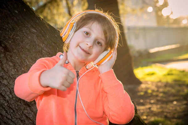 Молодая девушка слушает музыку в наушниках в парке — стоковое фото