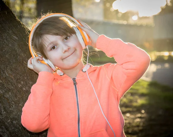 Menina é ouvir música com fone de ouvido para o parque — Fotografia de Stock