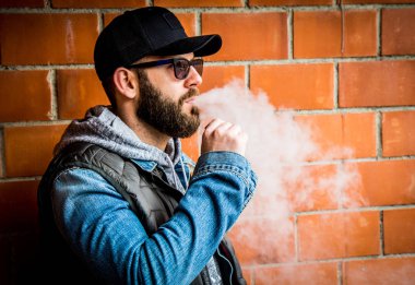 sakallı adam b duvarı yakınında elektronik sigara içiyor