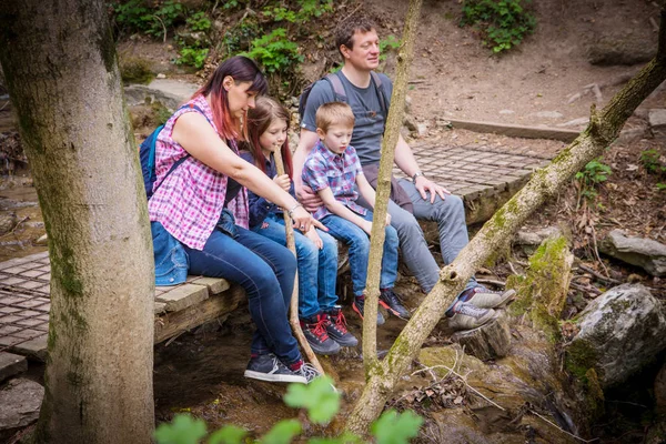 Heureux famille sont assis sur un pont en bois au milieu de pour — Photo