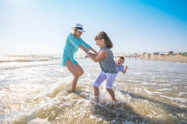 Mãe e seus filhos brincando no mar — Fotografia de Stock