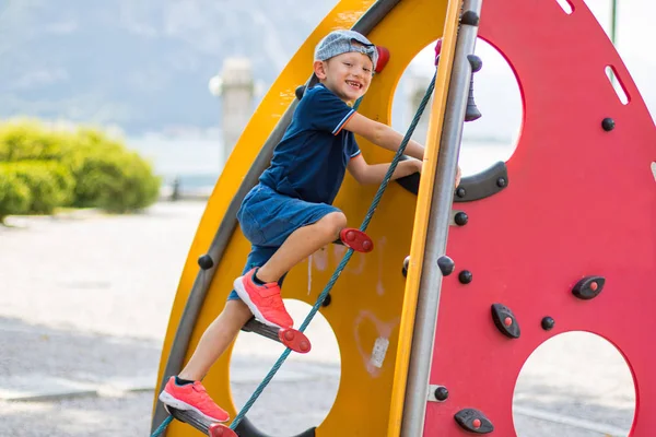 O menino está escalando no playground — Fotografia de Stock