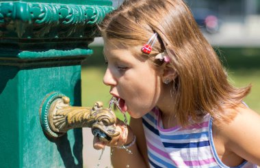 Parktaki su fıskiyesinden içen genç kız 