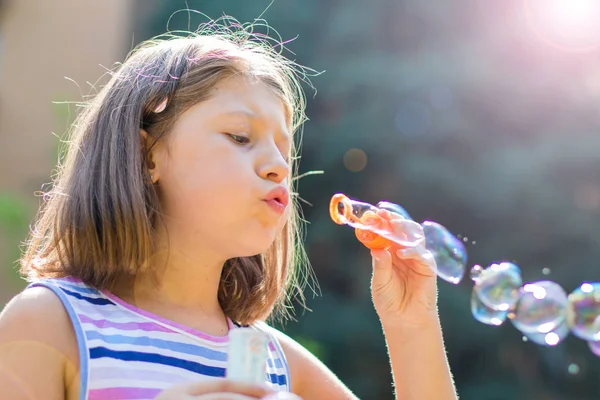 Mädchen pustet Seifenblasen in Park an einem sonnigen Tag — Stockfoto