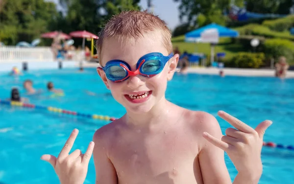 Mosolygó fiatal fiú, úszószemüvegek viselése a medencében — Stock Fotó