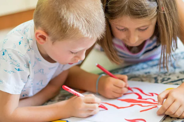 Brother and sister drawing on floor on paper. Preschool boy and — Stock Photo, Image