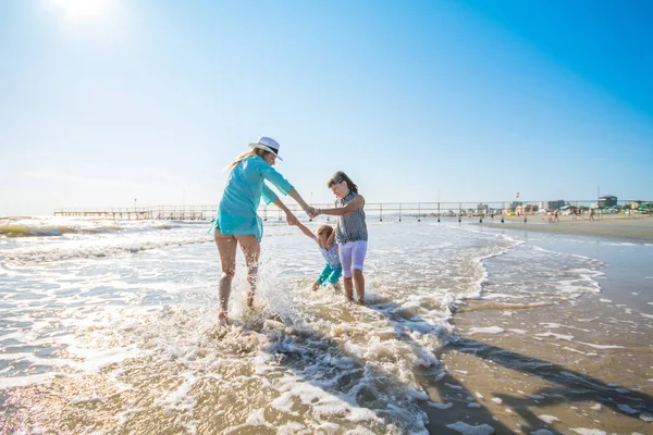 Mãe e crianças estão brincando no mar na praia — Fotografia de Stock