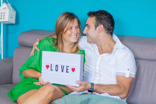 young couple in love sit on the sofa with love chart