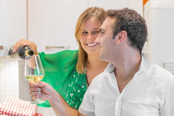 Hermosa pareja joven está bebiendo vino y sonriendo en la cocina a — Foto de Stock