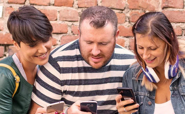 Freundeskreis schaut gemeinsam aufs Smartphone — Stockfoto