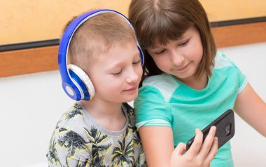 Erkek ve kız kardeş evdeki kanepede uzanmış selfie çekiyorlar.