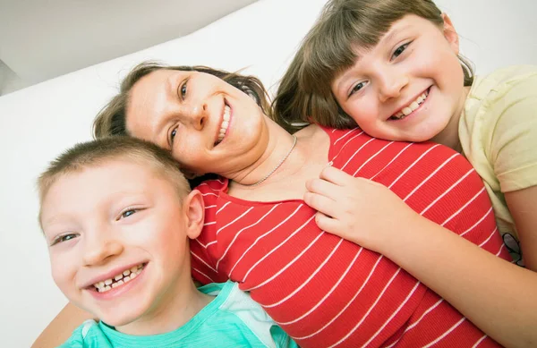 2人の子供と一緒に笑顔の母親がソファの上に横になって — ストック写真