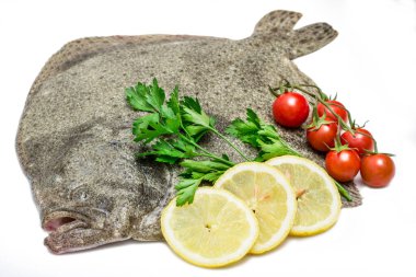 Limon dilimleri, kiraz domatesleri ve beyaz arka planda izole edilmiş maydanozlu çiğ turbot balığı.
