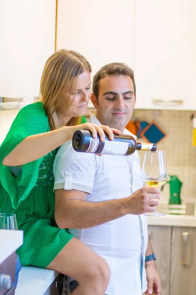 这对快乐的夫妇正在厨房里喝着一杯白葡萄酒 — 图库照片