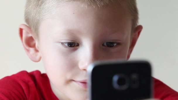 Jonge Jongen Kijkt Naar Zijn Mobiele Telefoon Speelt — Stockvideo