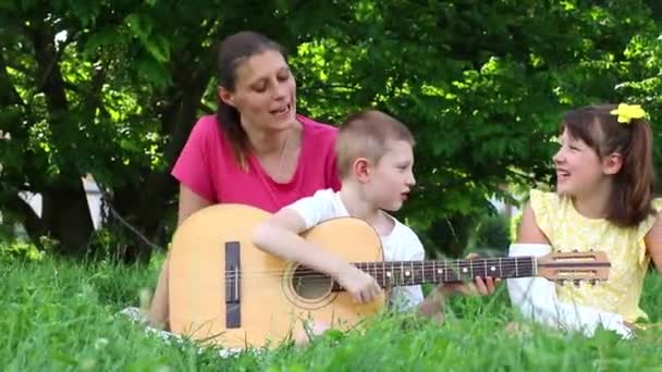 妈妈和她的两个孩子在公园里弹奏吉他 放松和户外生活的概念 — 图库视频影像