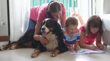 Bir anne ve çocuğu evde resim çizerken onlar da aile köpeğini şımartıyorlar. 