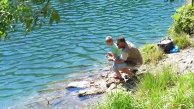 Baba ve oğul dağ gölünde alabalık avlıyor. Rahatlama ve sağlıklı aile hayatı kavramı.