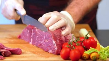 Çiğ et kesiyorum. Aşçı bir bıçakla tahtadan çiğ et kesiyor.