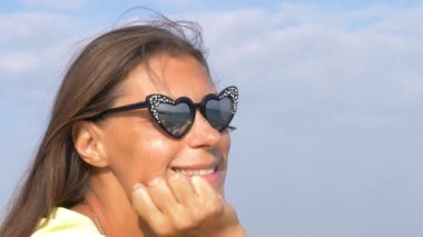 Denizde güzel bir kadın, güneş gözlükleriyle manzarayı yansıtıyor.