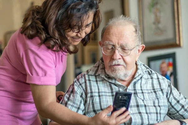 Leende Äldre Man Och Vårdgivare Med Smartphone Gör Videokall — Stockfoto