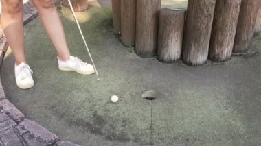 Mini golf ya da minyatür golf, putt-putt. - golf topunu deliğe sokan kadın..
