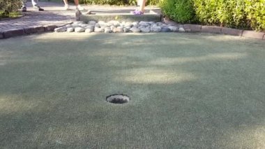 Mini golf ya da minyatür golf, putt-putt. - golf topunu deliğe sokan kadın..