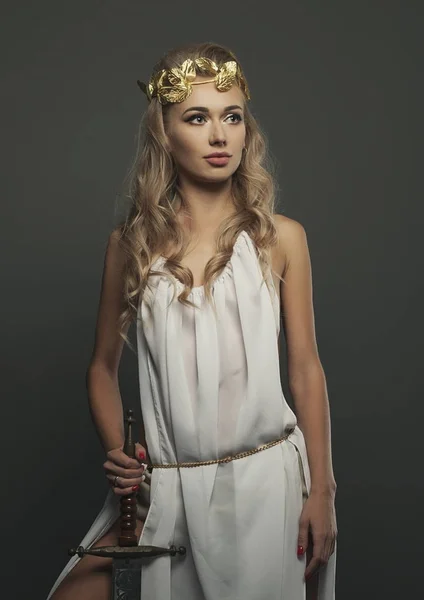 goddess young woman with sword on dark bg studio shot