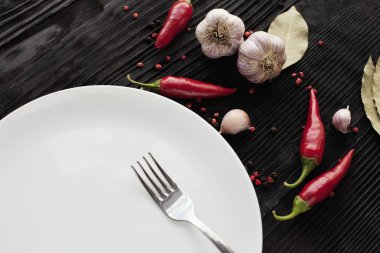 Siyah ahşap arka plan üzerinde plaka çatal sarımsak kırmızı biber