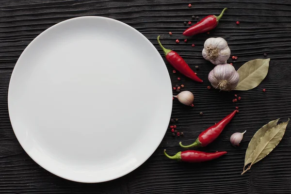 Teller Knoblauch rotes Chili auf schwarzem Holzhintergrund — Stockfoto