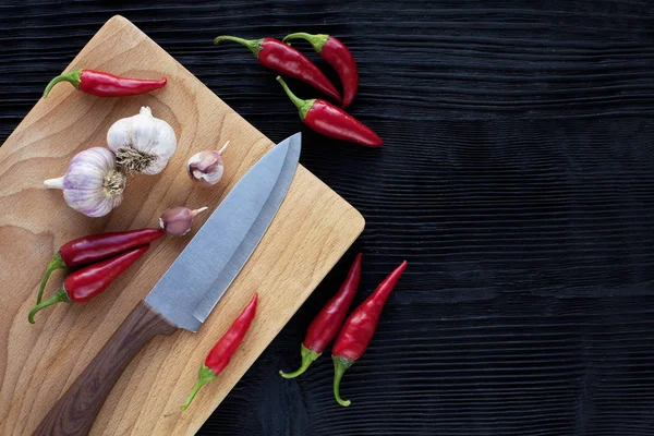 Coltello chef aglio bordo di legno chili su uno sfondo scuro — Foto Stock