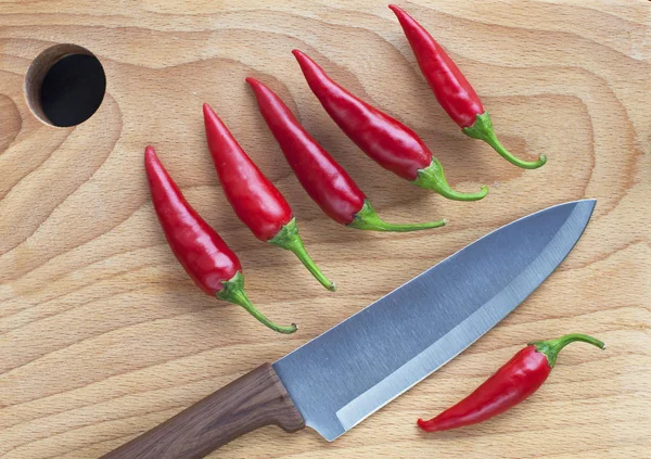 Nóż kucharz czerwona papryka chili na drewnianym tle — Zdjęcie stockowe