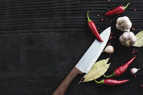 Nóż czosnek czerwona papryka chili na czarnym drewnianym tle — Zdjęcie stockowe