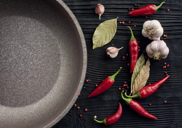 Knoblauch rote Chilipfanne auf schwarzem Holzhintergrund — Stockfoto