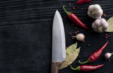  siyah ahşap arka plan üzerinde bıçak şef sarımsak biber