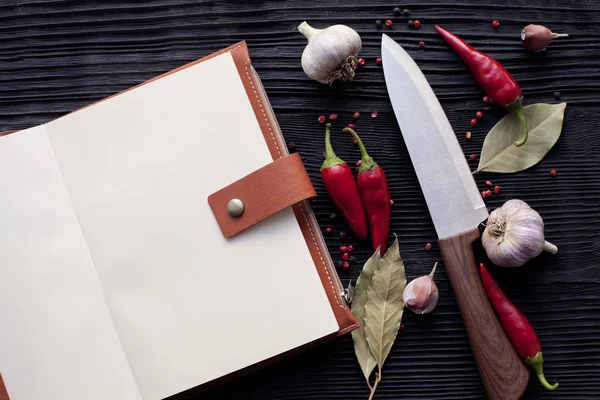 Notatnik szef kuchni nóż czosnek chili i na drewnianym ciemnym backgro — Zdjęcie stockowe