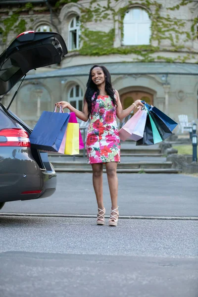 若いアフリカの女性は車のトランクに彼女の購入を入れている — ストック写真