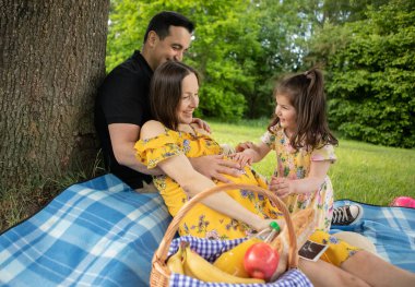 Hamile anne, baba ve üç yaşındaki kız piknikteler.