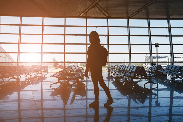 Woman tourist with a backpack waiting for her flight in the airport lounge room