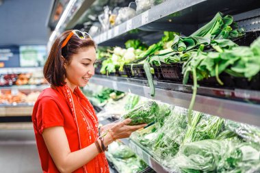 Bir kadın bir süpermarkette yeşil sebzeler, bir tarım kavramı ve bir vejetaryen diyet seçer