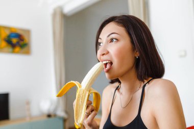 Genç kadın evinde muz yemek