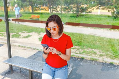 Otobüs durağında akıllı telefon kullanan şık hippi kız