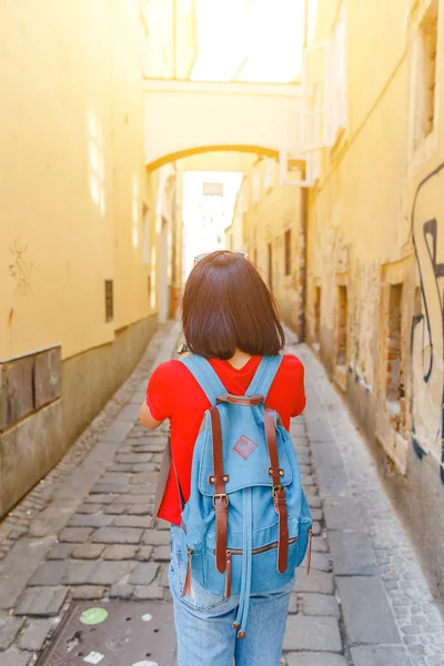 Woman tourist with a backpack travels through narrow European streets