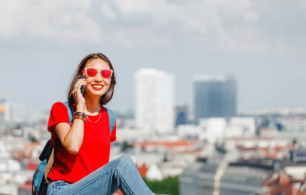 Счастливая Женщина Красном Разговаривает Смартфону Фоне Современного Европейского Города — стоковое фото