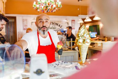 12 Mayıs 2018, Slovakya, Bratislava: karizmatik ve yakışıklı Şef sakallı gelato mağazada alışveriş için dondurma satıyor