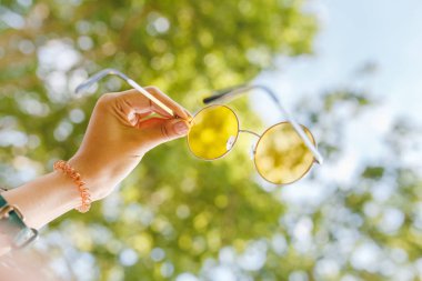 Yeşil park görünümü ile sarı hipster güneş gözlüğü